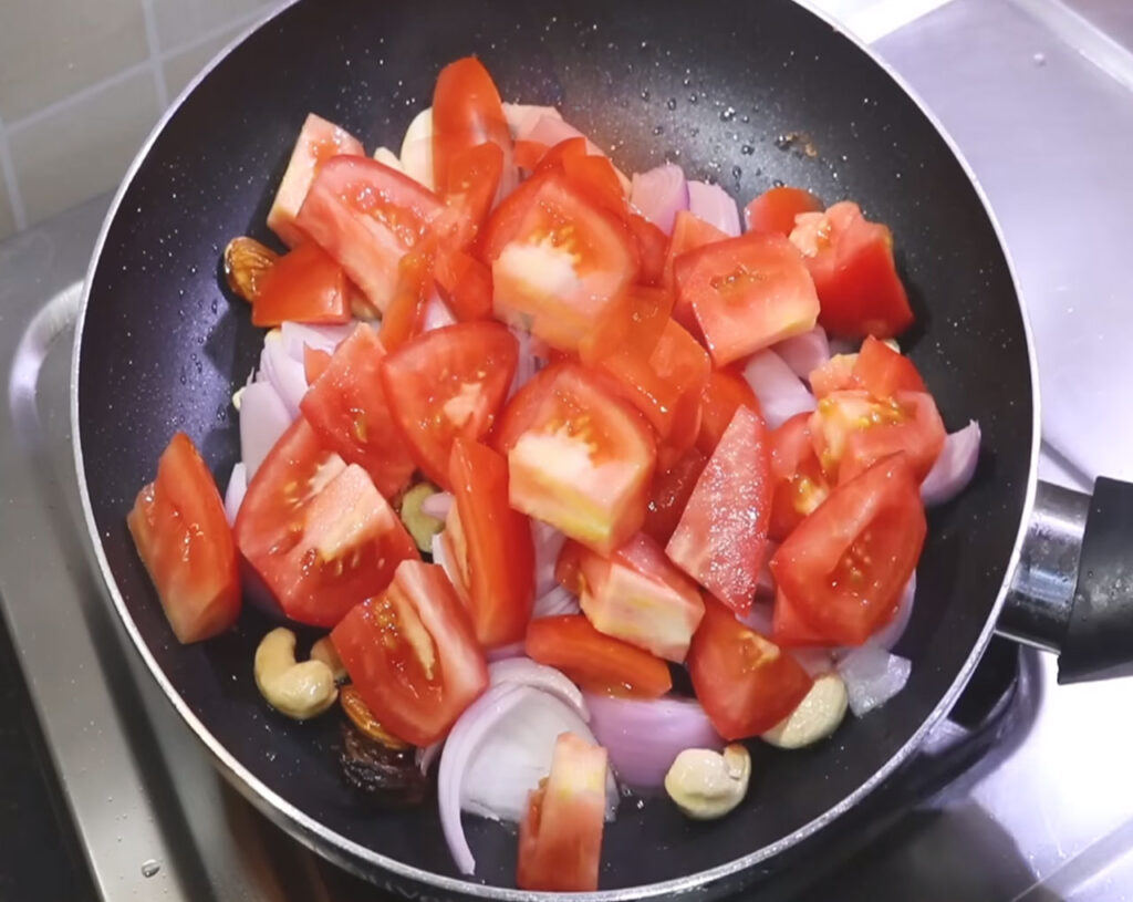 Tomatoes and cashew nuts added to a sauté pan with onions for Shahi Paneer curry paste