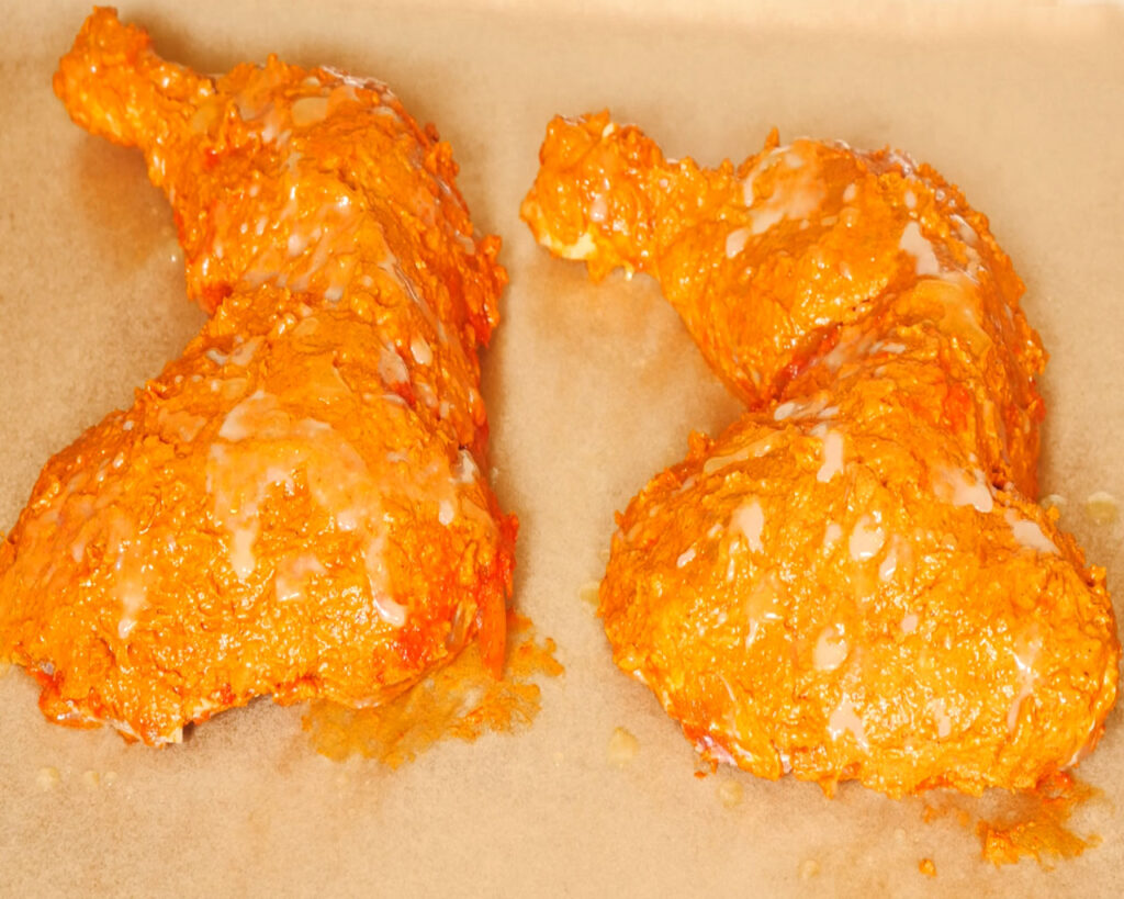 Marinated chicken pieces on baking tray for baking tandoori chicken