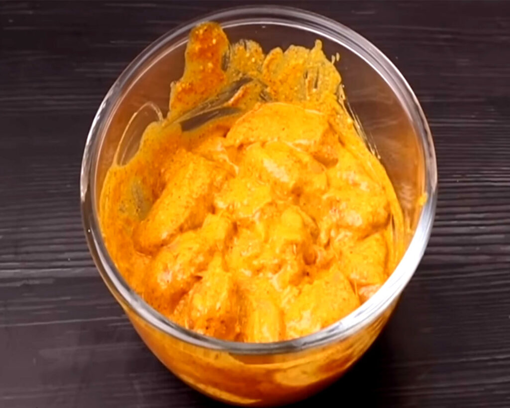 Chicken pieces fully coated in marinade and resting in a covered bowl