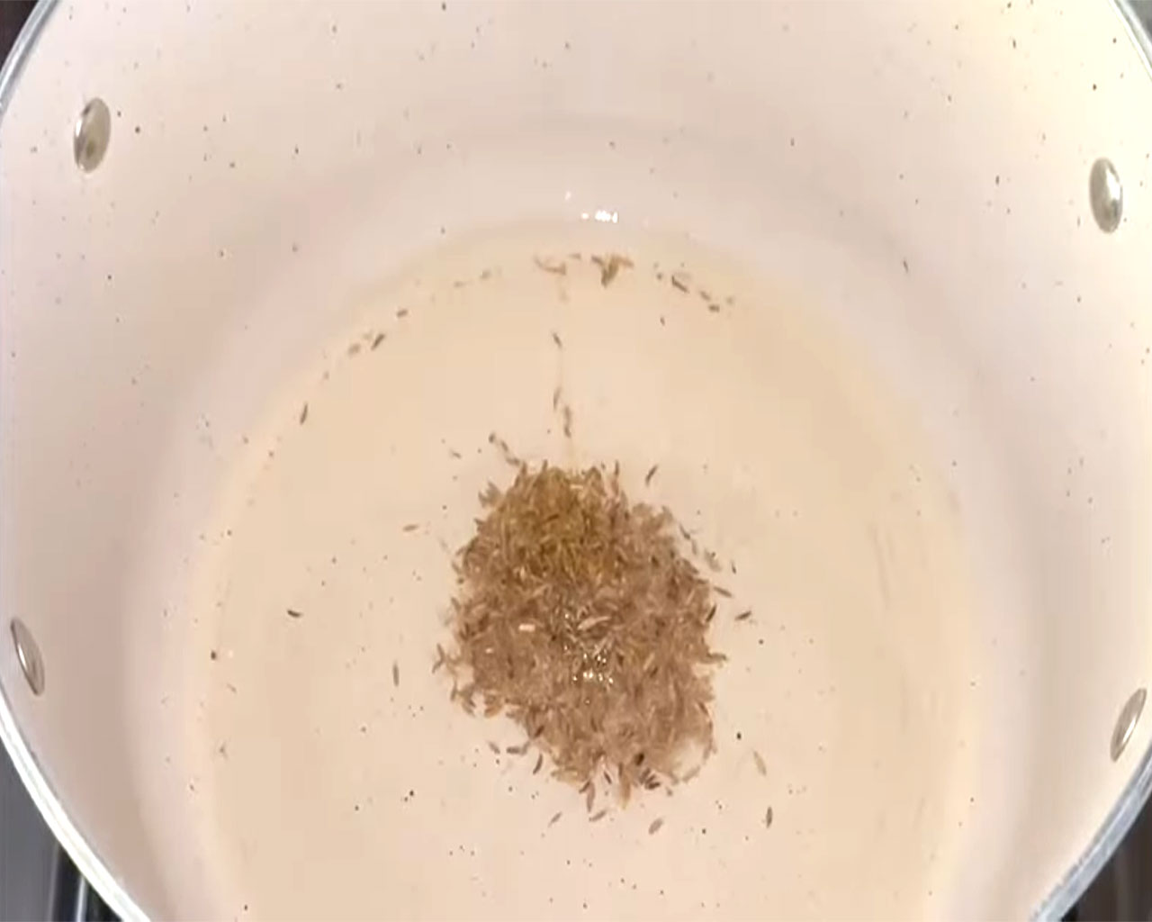 Cumin seeds sizzling in hot oil in a frying pan