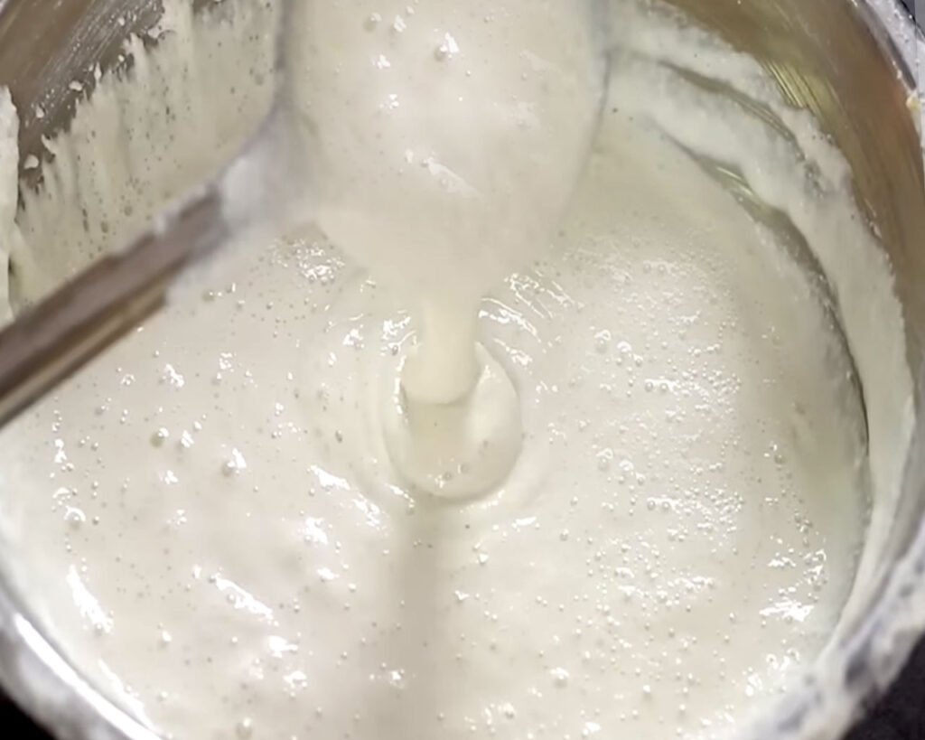 A close-up of dosa batter after fermentation, showing a risen texture with tiny air bubbles on the surface, indicating it’s ready for making dosas.