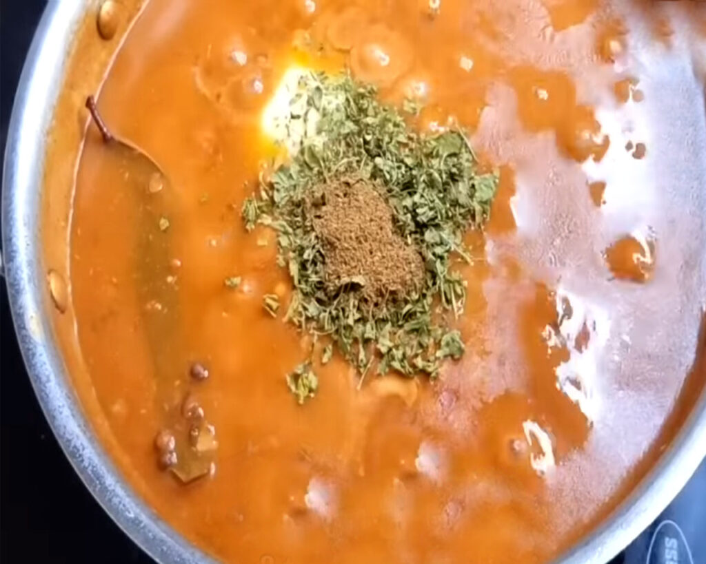 Cream, butter, and spices added to simmering Dal Makhani.