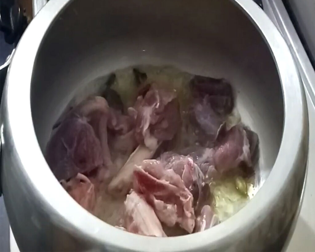 Fresh mutton pieces sizzling in the cooker as they are being seared with spices.