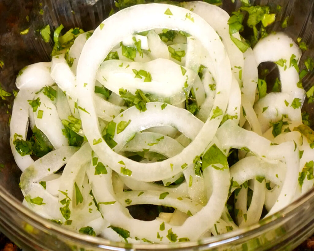  Mixing onion rings, chopped cilantro, and lemon juice for garnish