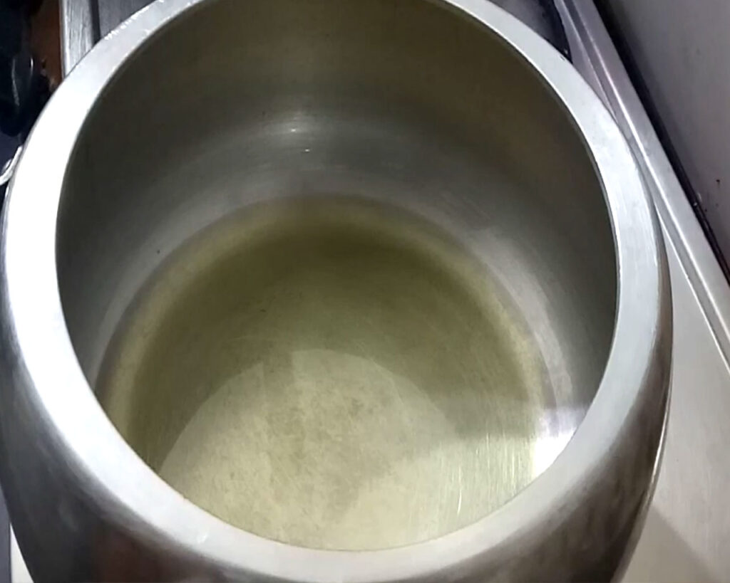 Ghee melting in a pressure cooker over medium flame, ready for cooking Rogan Josh recipe