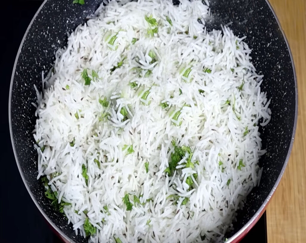 Steaming hot jeera rice served with curry and fresh coriander garnish