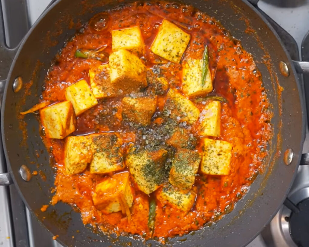 Paneer cubes added to rich tomato-based butter masala with cream and kasuri methi