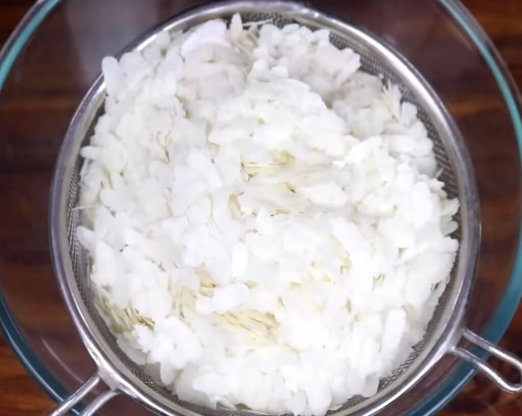 Rinsing flattened rice (poha) in a colander under running water and drain it and put aside