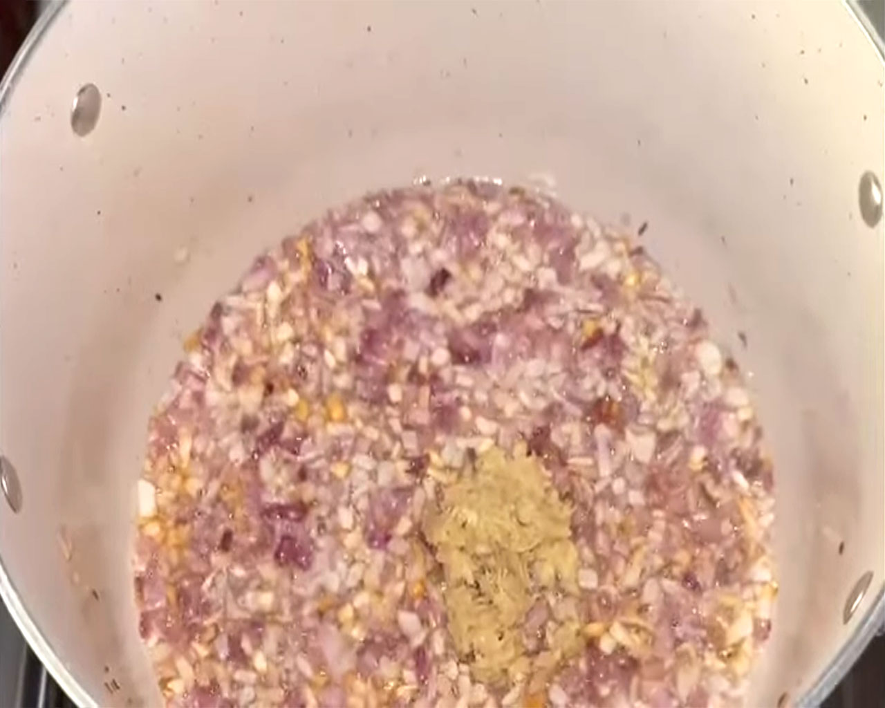 Ginger-garlic paste being added to sautéed onions