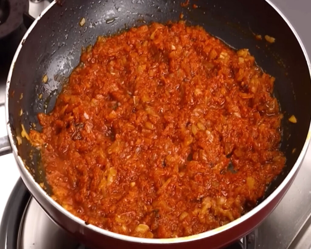 Spices, ginger-garlic paste, and chopped onions cooking in oil in a pan for chicken tikka gravy