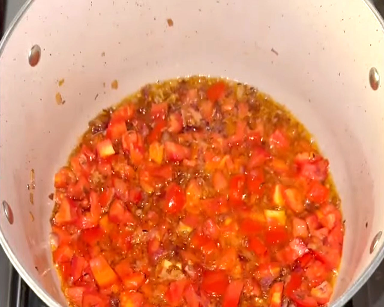 Chopped tomatoes cooking with onions under a lid