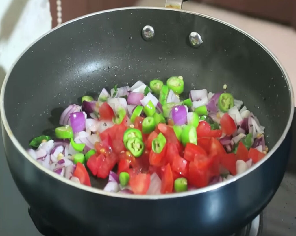 Chopped tomatoes sautéing in pan for traditional South Indian upma