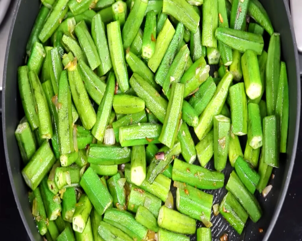 add sliced bhindi on top of onion in pan for preparing bhindi masala
