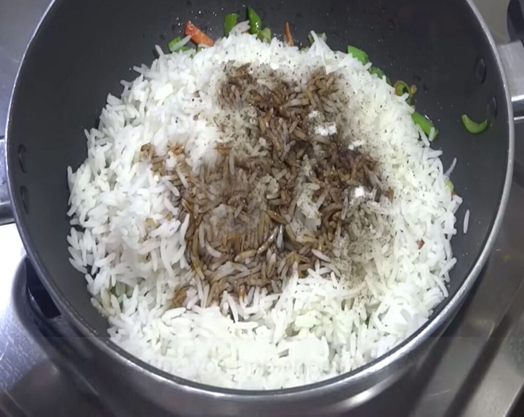 Soy sauce and vinegar being added to rice and vegetables in the pan