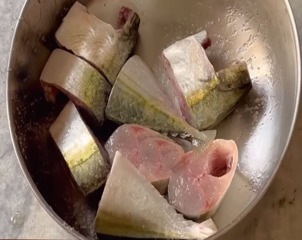 Cleaned and sliced fish pieces marinated with salt and turmeric for Goan fish curry.