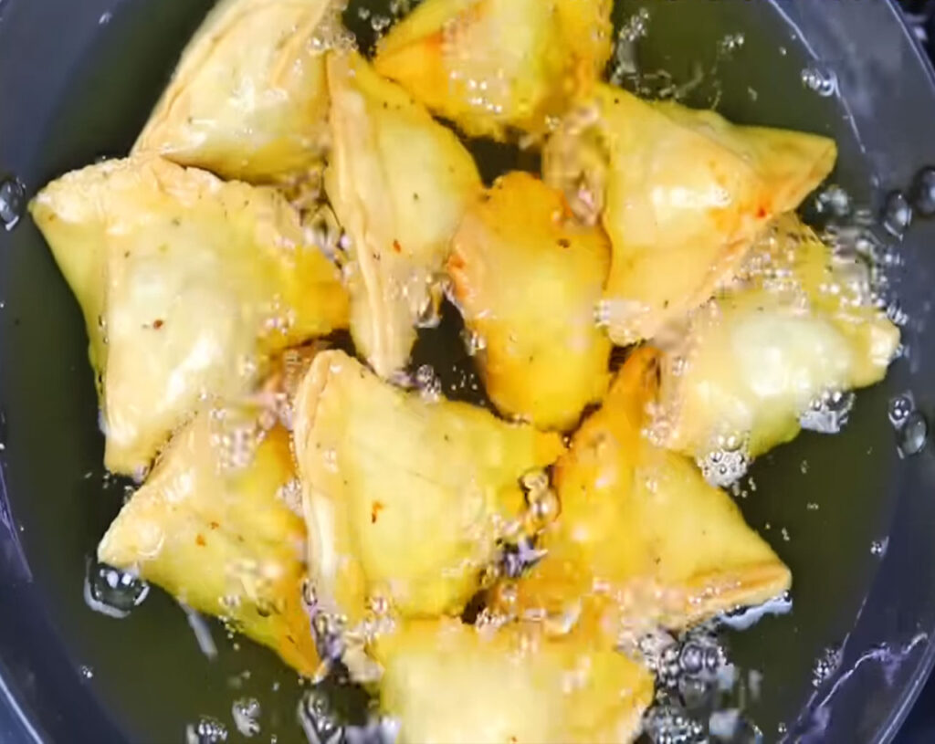 golden brown crispy samosa frying in oil almost ready to serve