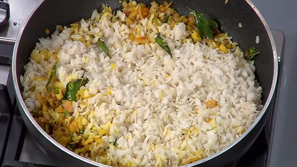 Onions being sautéed with mustard seeds, curry leaves, and green chilies for Kanda Poha
