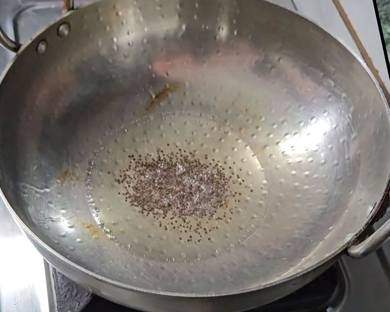 Mustard seeds being sautéed in a wok for Palak Paneer
