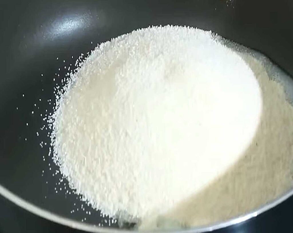 Roasting rava (semolina) in a pan until golden for making upma.