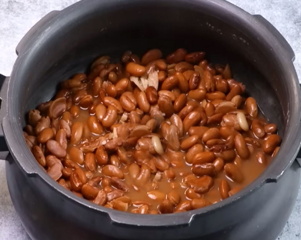 Boiled rajma in cooker with whole spices removed, showing perfectly cooked soft kidney beans.