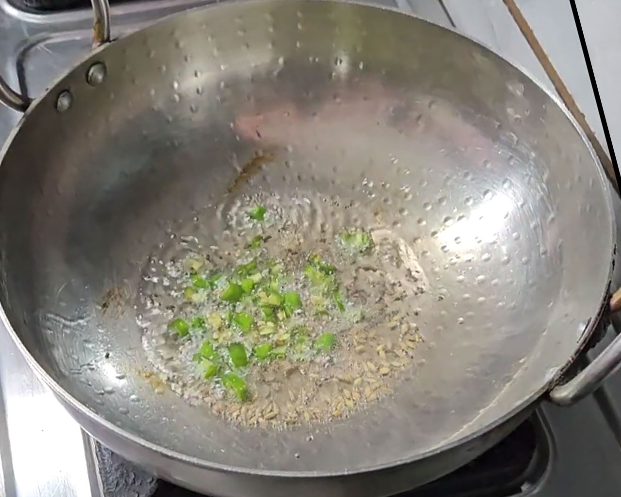 Chopped green chilies  being sautéed in a wok for Palak Paneer