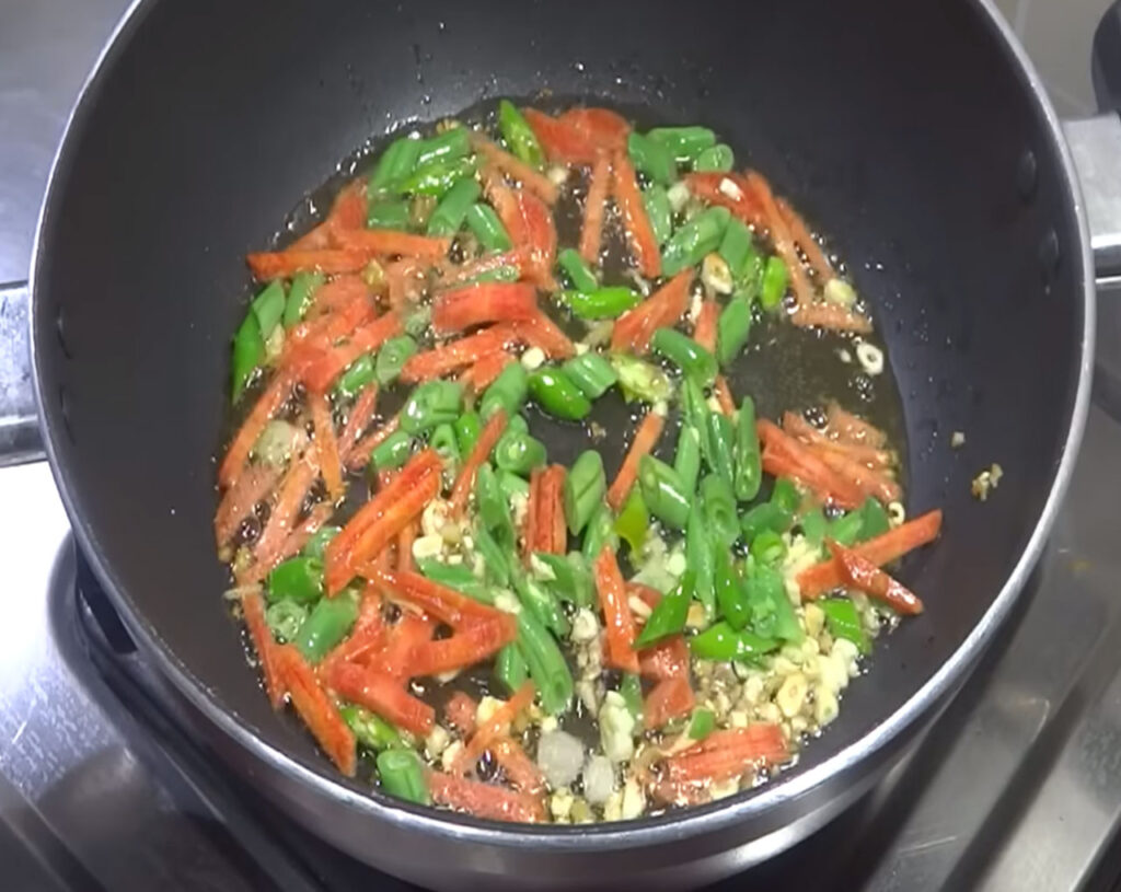 Chopped vegetables being stir-fried on high flame for Veg Fried Rice