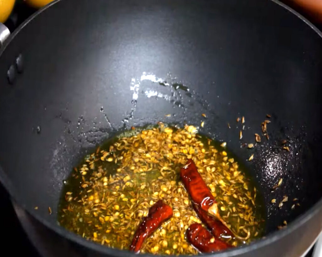 Adding tadka ingredients for Jeera Aloo.