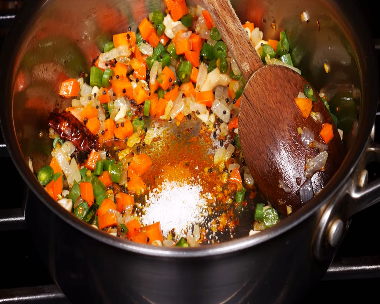 Mixing carrots, salt, and turmeric with vegetables