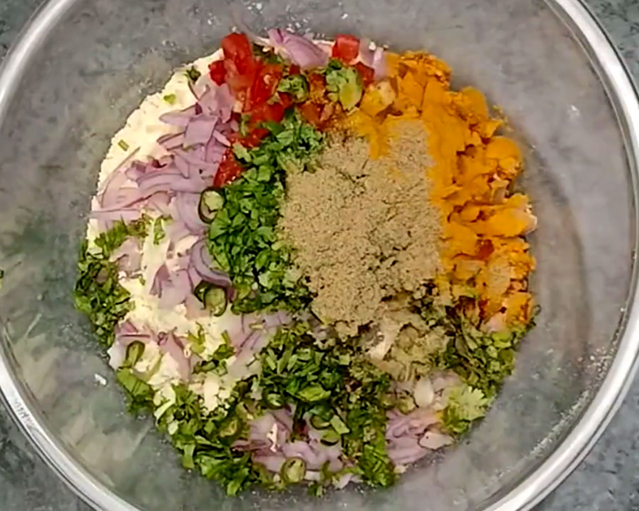 Adding spices to chilla batter: turmeric, red chili powder, chaat masala, and salt.