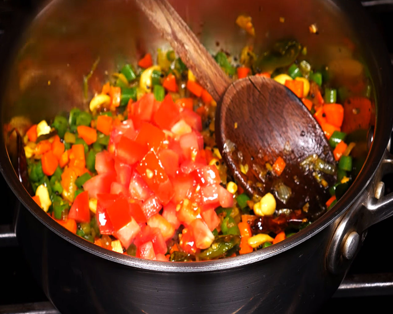 Alt Text: Adding chopped tomato and asafoetida into cooked vegetables