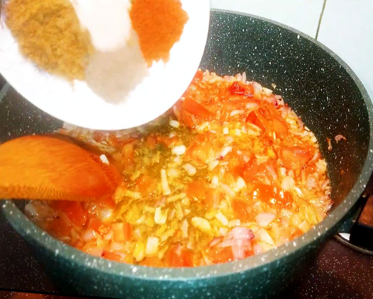 Indian spices added to onion-tomato masala in a pan