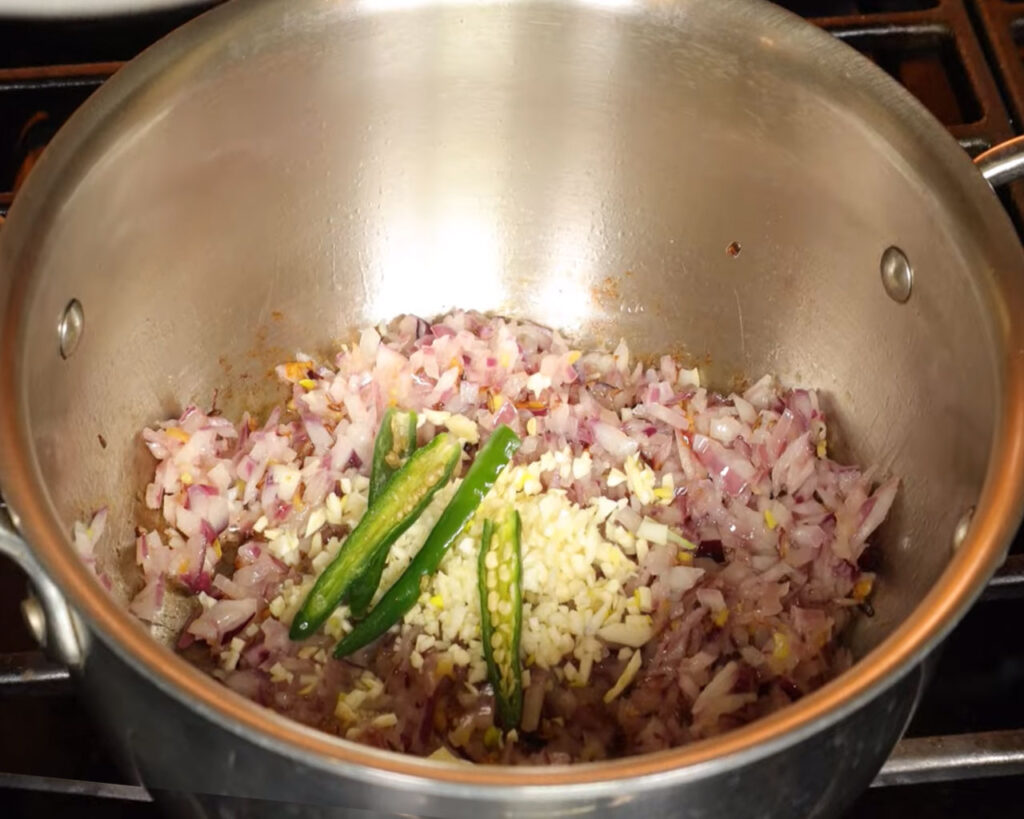Garlic and green chilies sautéing in a wok to add flavor to curry