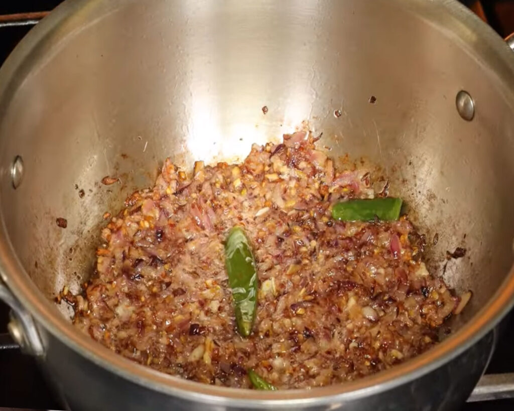 Garlic and green chilies sautéing in a wok to add flavor to curry