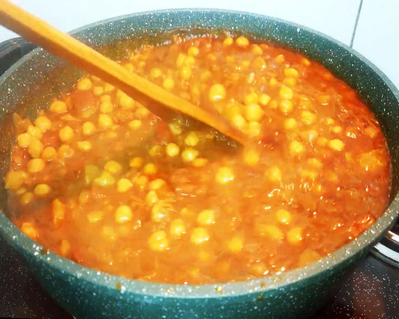 Tamarind pulp being mixed into spicy chana curry