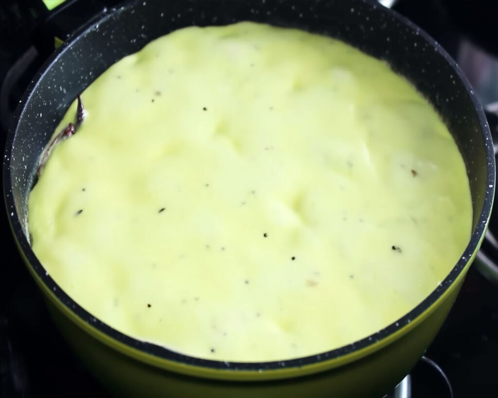 Boiling kadhi on low flame to thicken without covering the pan.