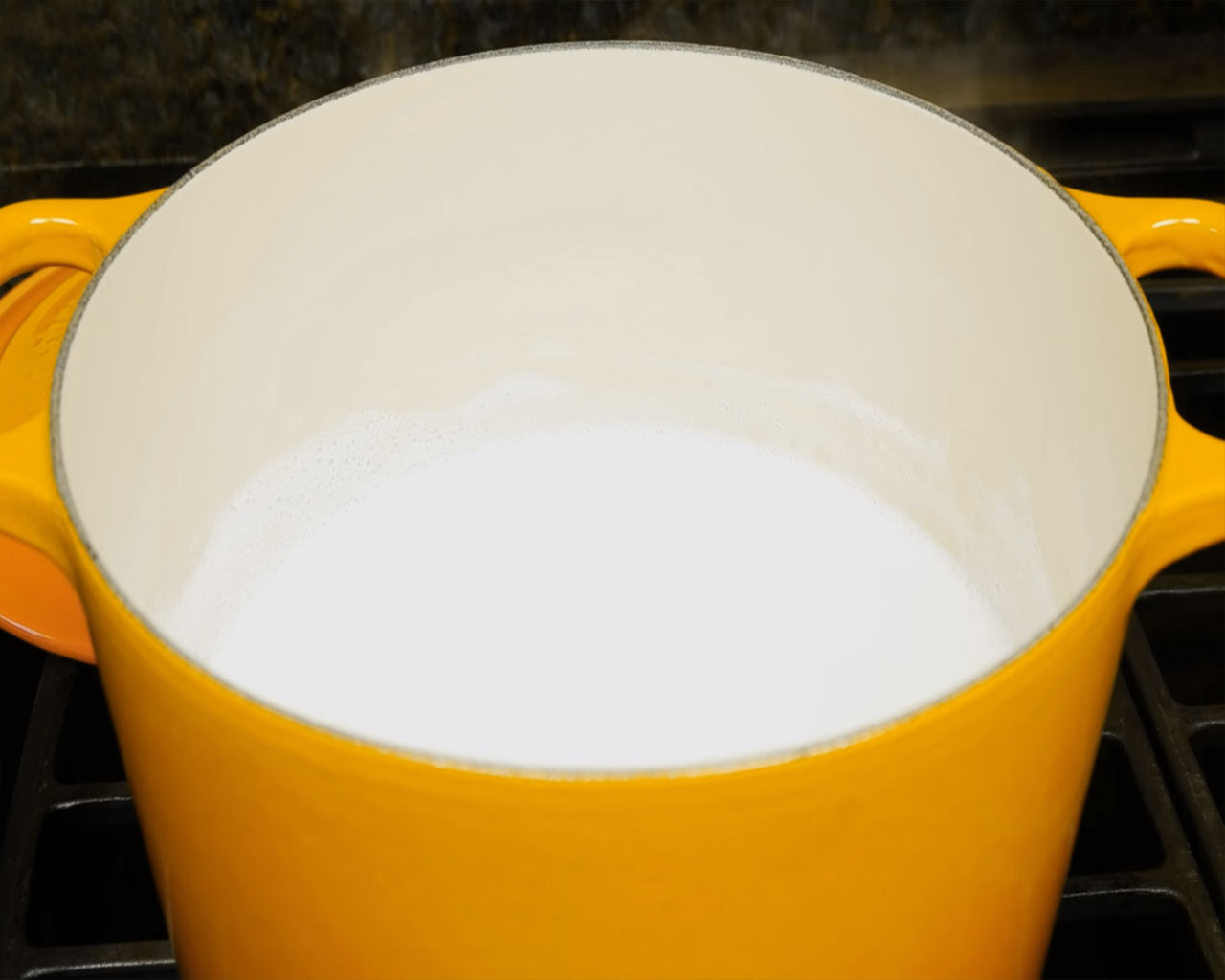 Whole milk boiling in a heavy-bottomed pot for making traditional Indian rice pudding or kheer.