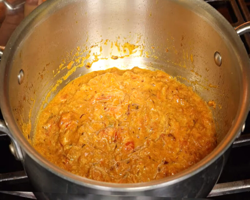 Mixing yogurt into tomato masala to create creamy cauliflower curry gravy