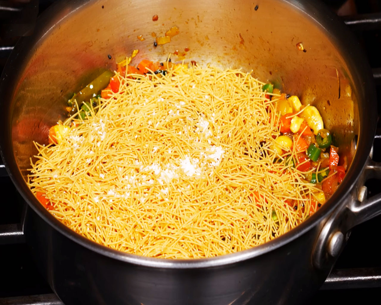 Adding salt to roasted vermicelli with vegetables