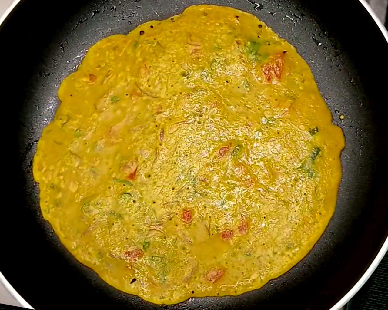 Cooking the chilla on low heat, covering with a lid until golden brown.