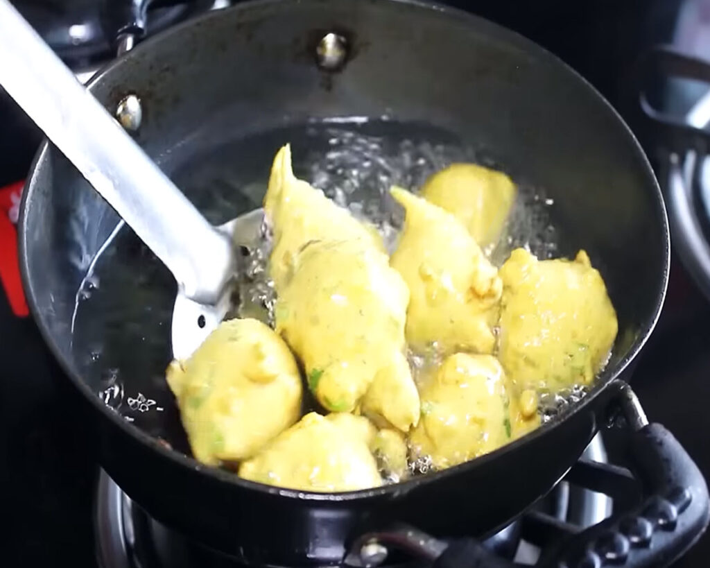 Frying besan pakoras until golden brown for Kadhi Pakora.