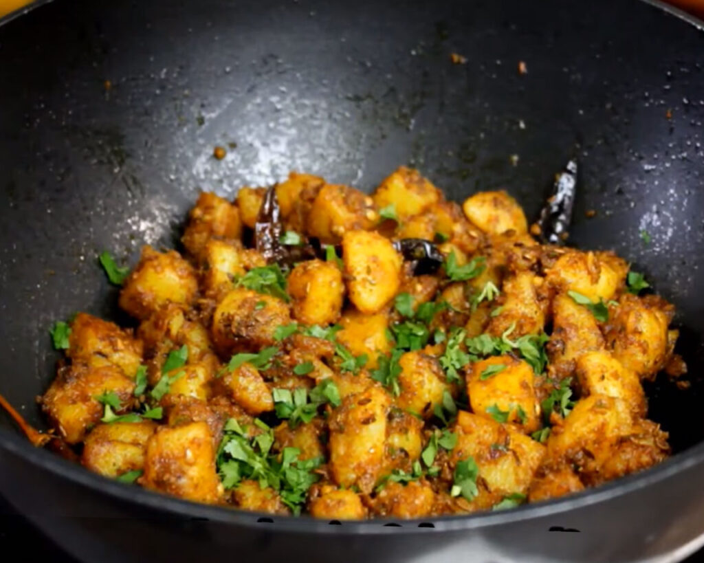 Garnishing Jeera Aloo with coriander leaves