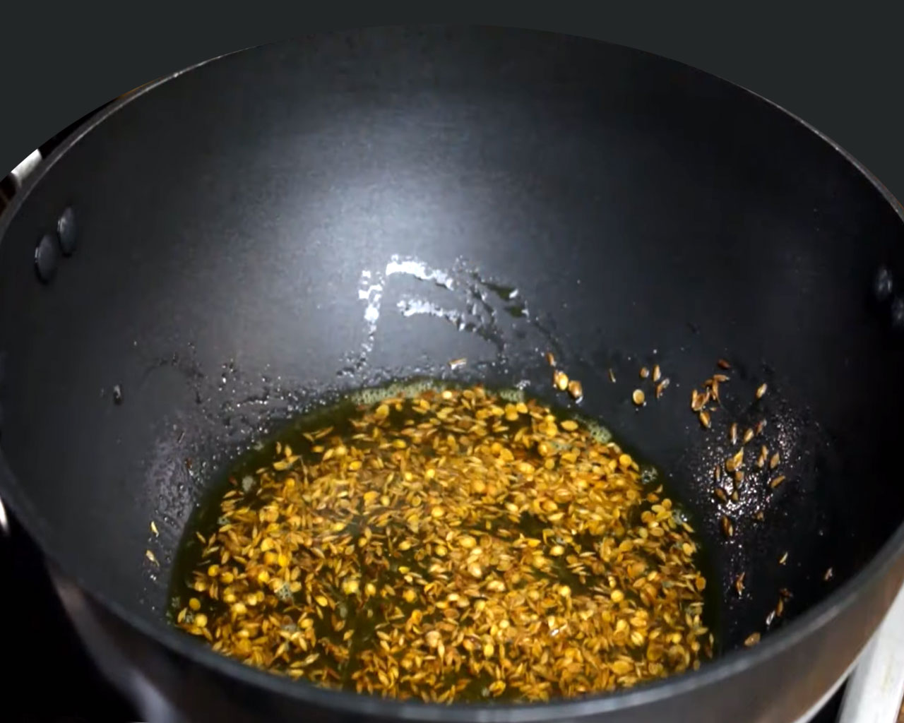 Preparing the tadka (tempering) with cumin and coriander seeds in mustard oil for Jeera Aloo.