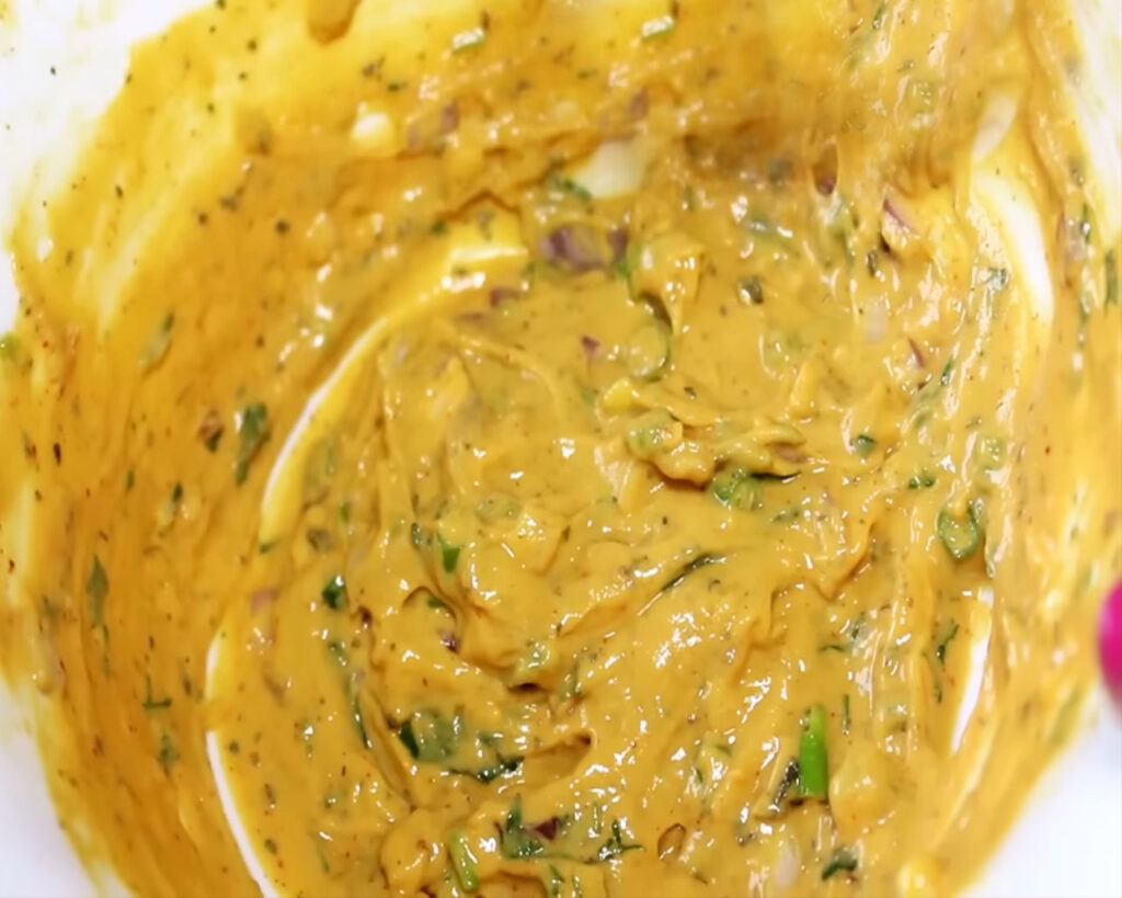 Mixing chickpea flour (besan) with spices and water to make the batter for Kadhi Pakora.