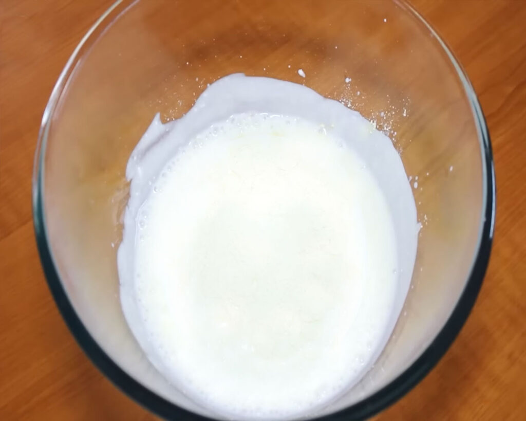 Whisking yogurt (curd) or buttermilk to prepare the base for Kadhi Pakora.