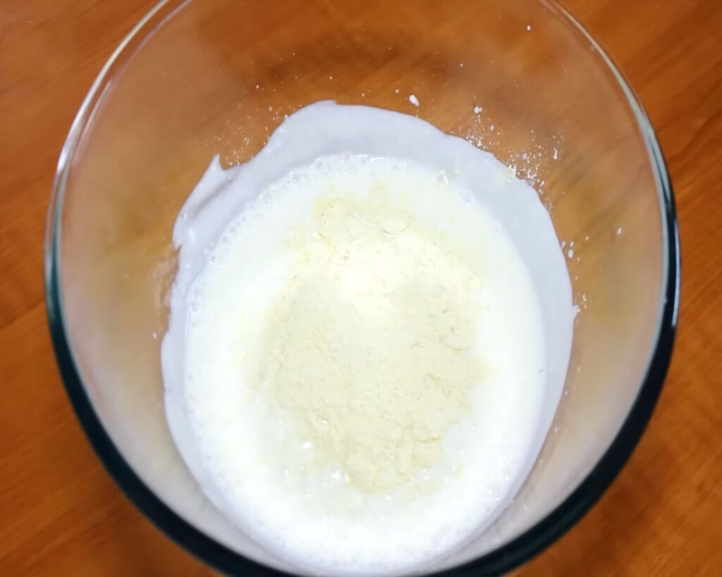 Adding besan to yogurt and mixing to create the smooth kadhi batter.