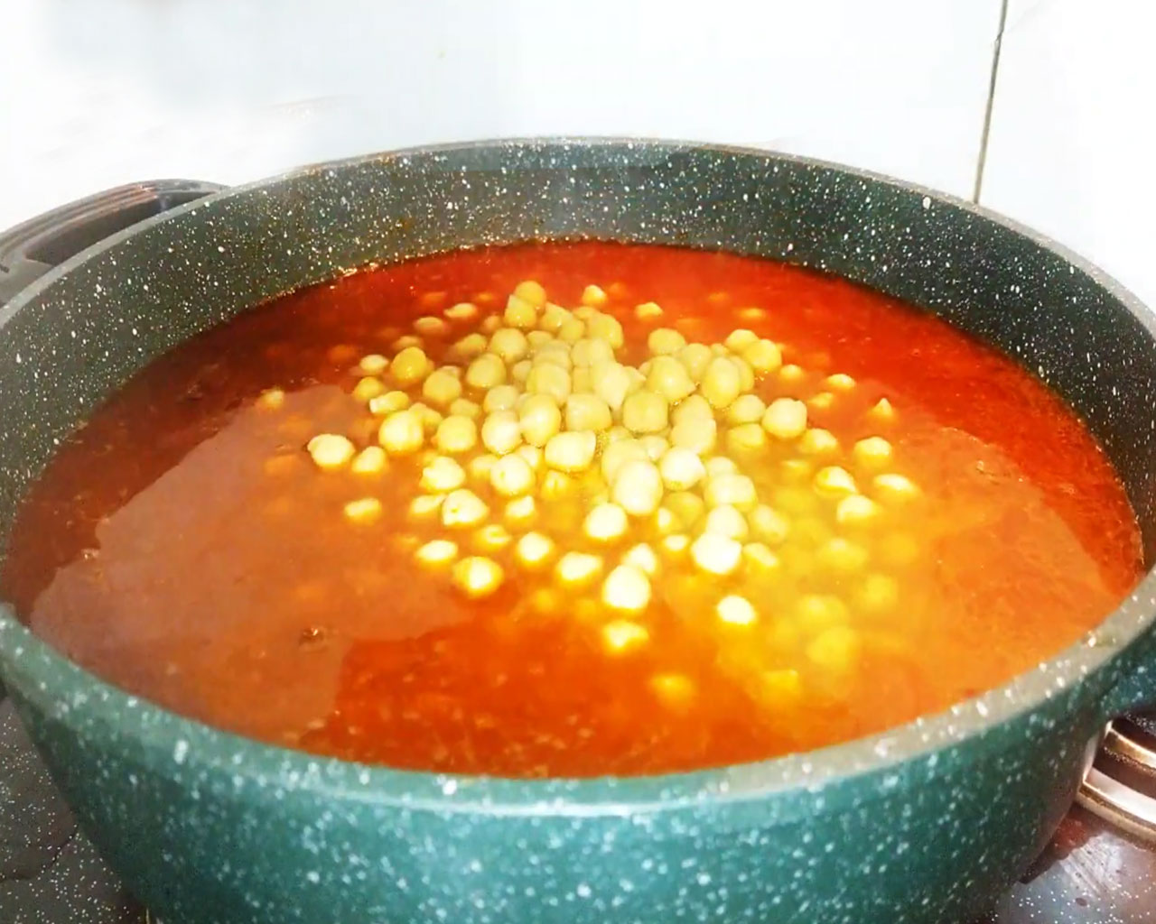 Boiled chickpeas added to thick masala gravy in a pan