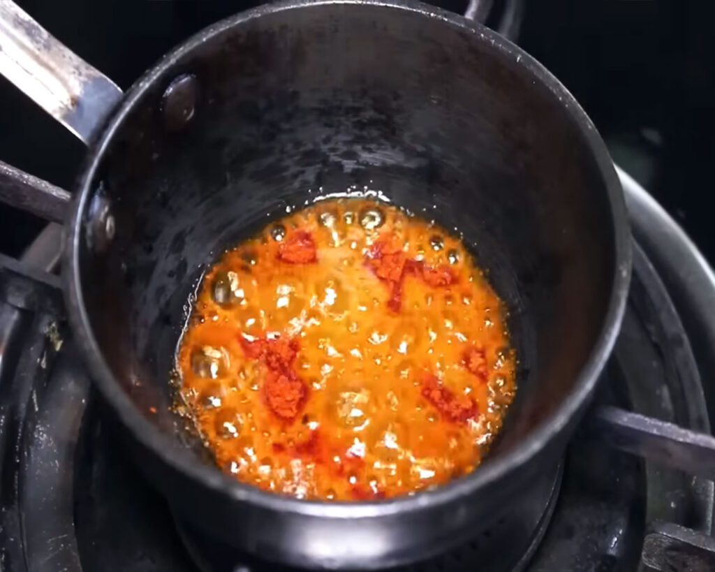 Preparing a red chili powder tadka to add flavor to Kadhi Pakora.