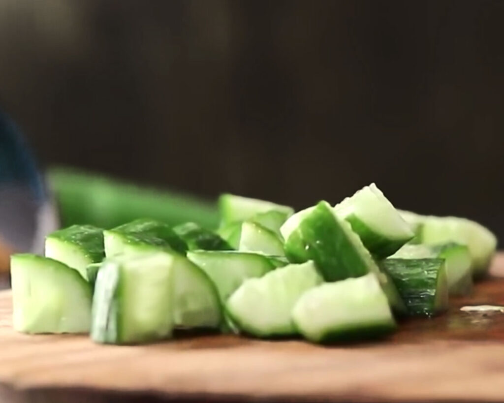 Thin slices of cucumber on a chopping board with a knife beside them