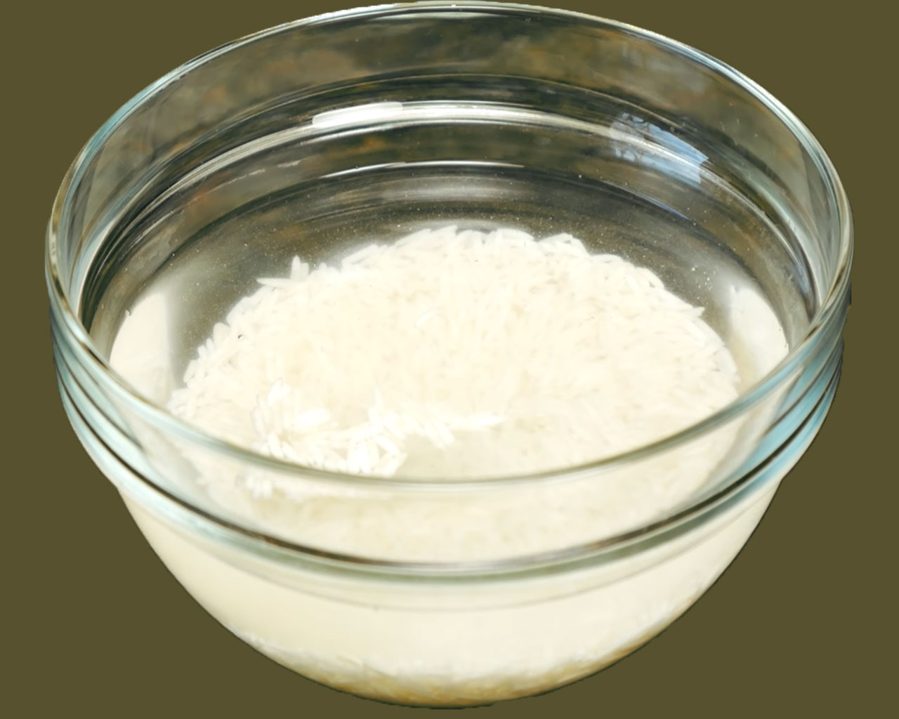 A bowl of basmati rice being rinsed and soaked in water to prepare creamy rice kheer