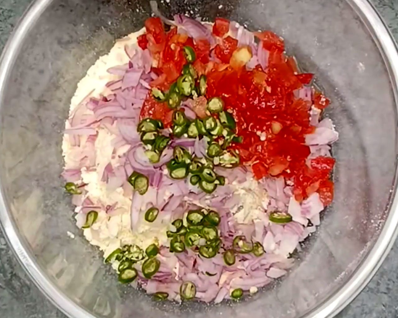 Adding tomatoes and green chilies to make chilla batter